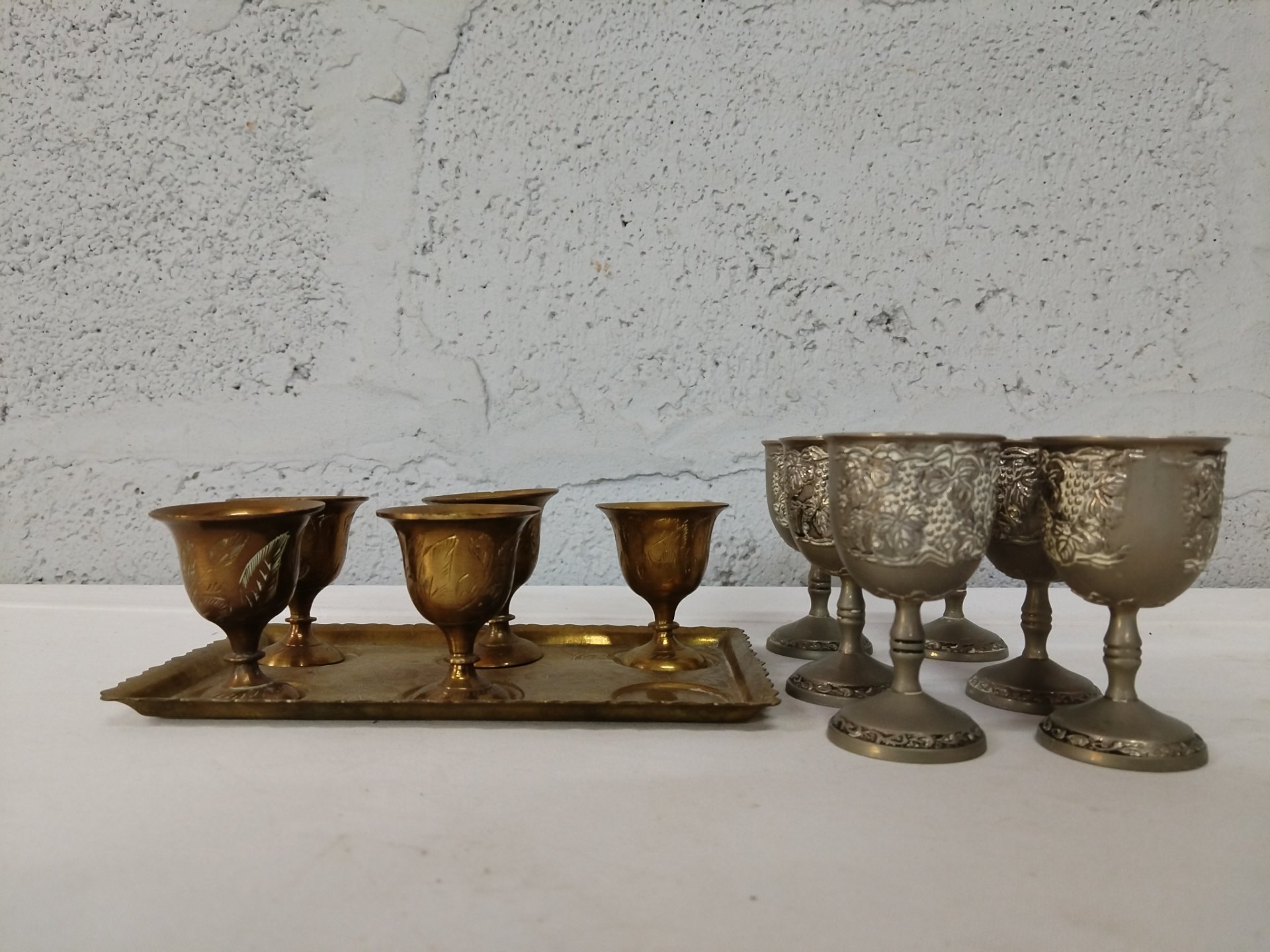 Mixed lot of small metal goblets & tray — 6 gold‑tone cups on tray + 6 ornate silver‑coloured stem goblets