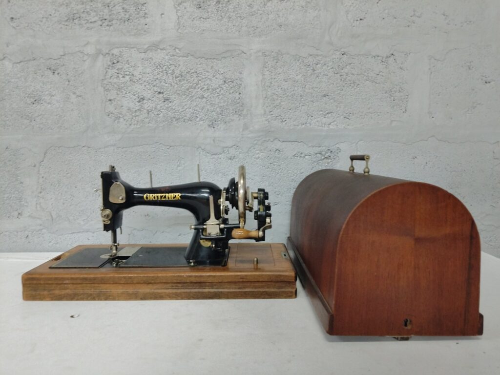 Vintage GRITZNER hand-crank sewing machine on wooden base with domed cover