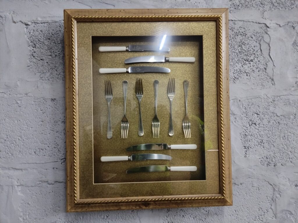 Framed shadow-box wall display: 6 knives (white handles) & 6 forks — decorative gilt frame