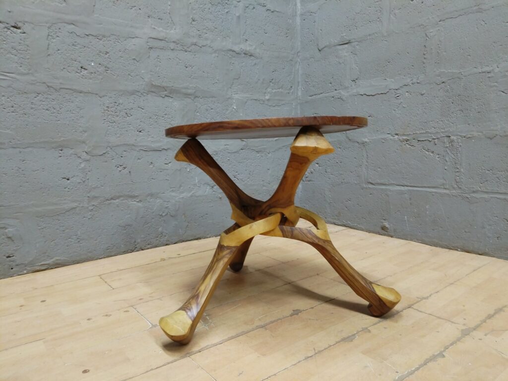 Carved wooden round side table with sculptural three‑leg base