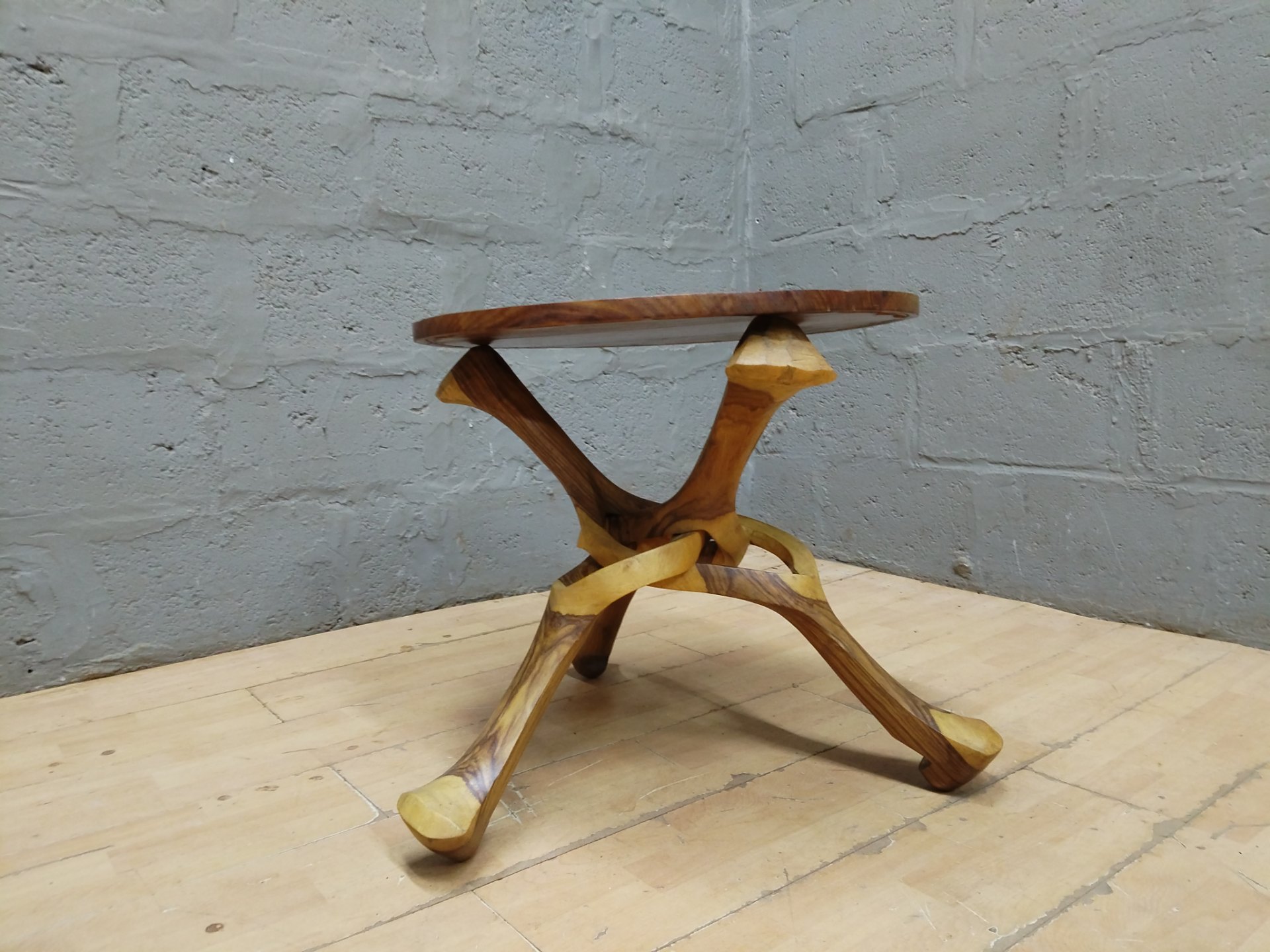 Carved wooden round side table with sculptural three‑leg base