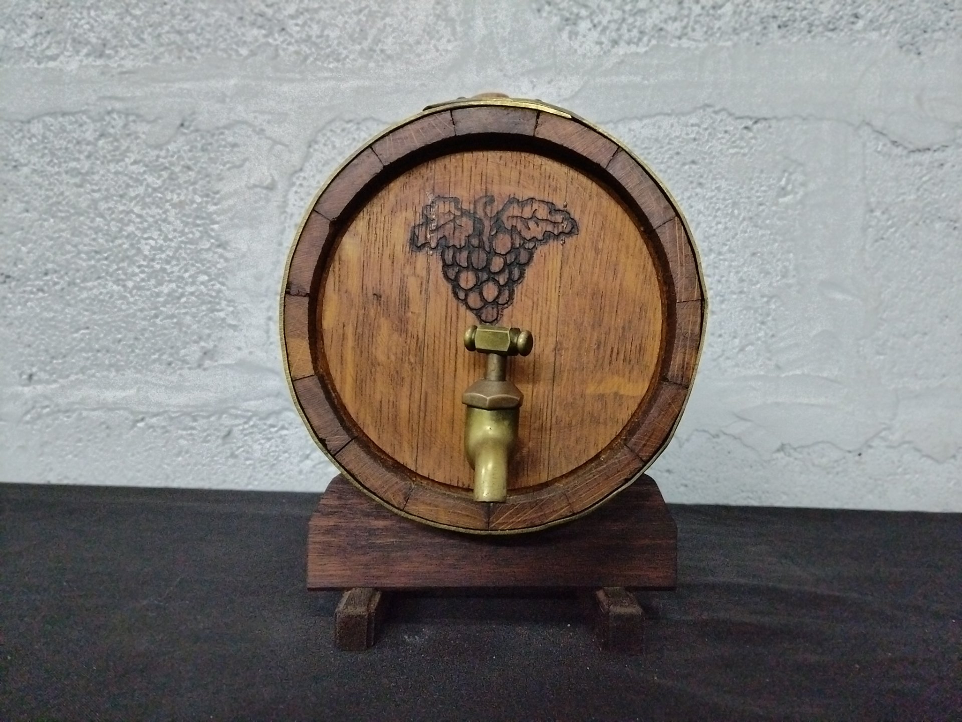 Small wooden barrel cask on stand with brass-coloured spigot — decorative, aged with hairline cracks