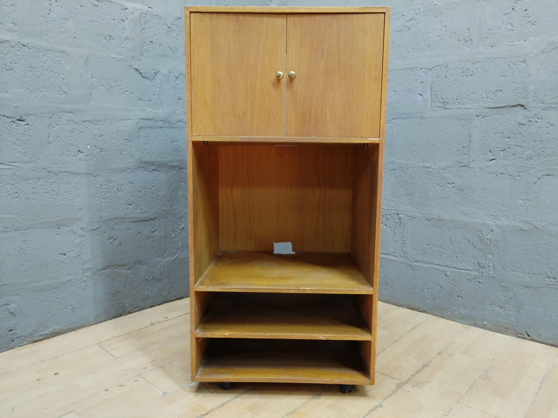 Tall wooden storage cabinet on castors with top double-door cupboard and open shelves