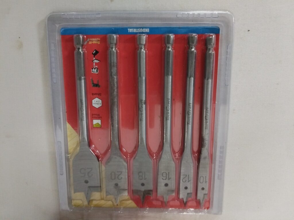 Mixed hole-saw & spade bit set in red case — 6.35mm (1/4″) shank, 10–25mm spade bits, used with light surface rust