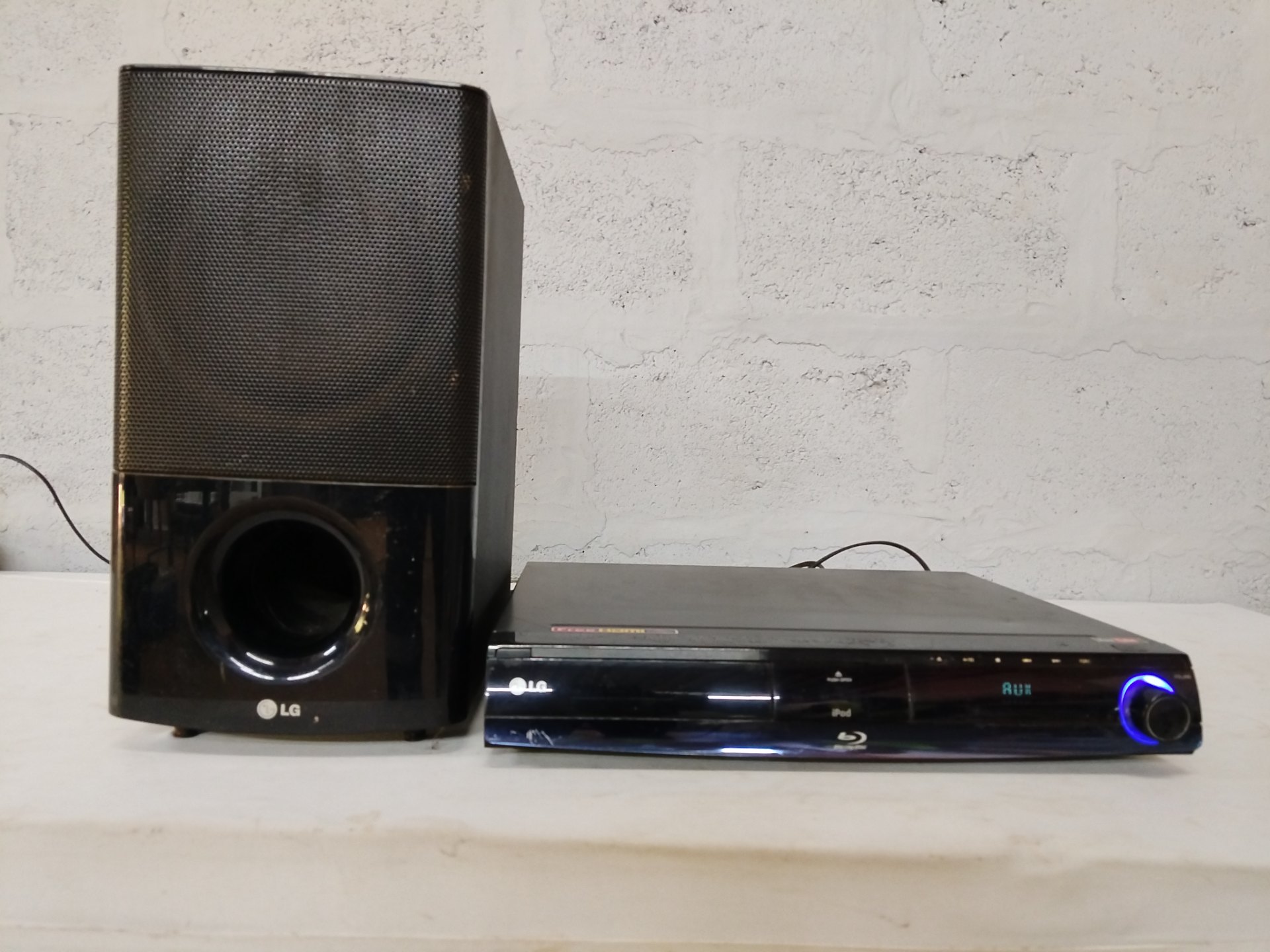 LG Blu‑ray Home Theatre HB954SA‑AP — main unit + large subwoofer, powers on (display lit)