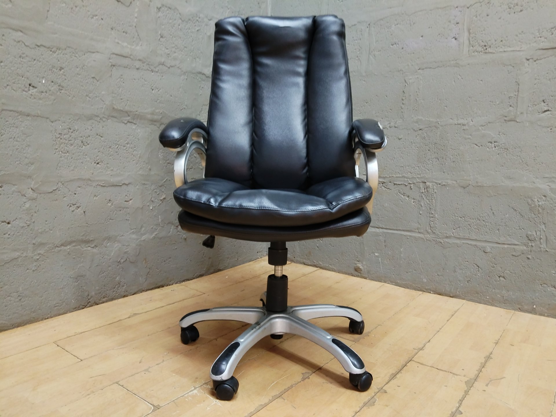 Black faux-leather high-back office swivel chair — adjustable, casters, visible armrest wear