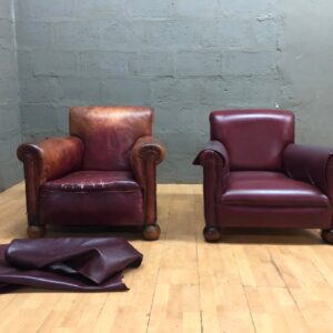 Pair of leather club armchairs — one heavily worn, one good, loose leather covers included
