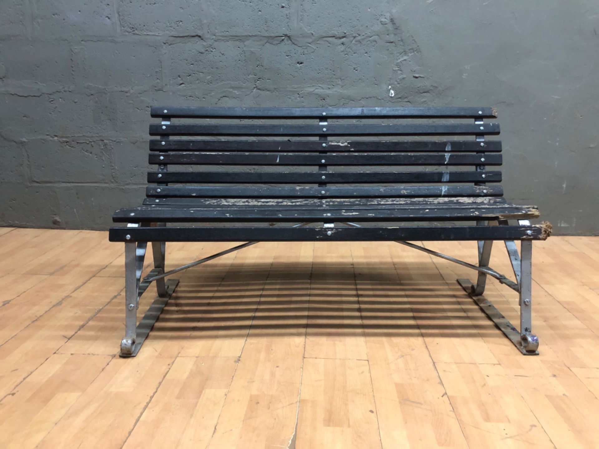 Outdoor slatted park bench — metal frame, wooden slats (needs repair)