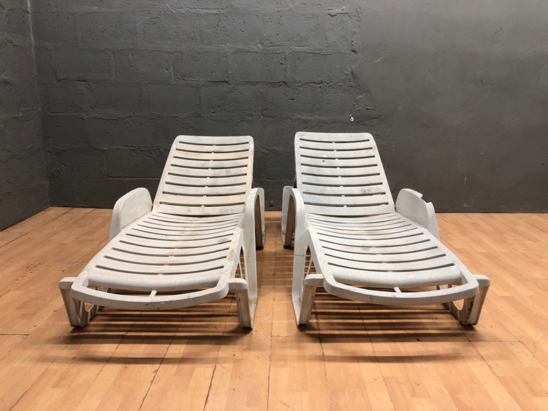 Pair of white plastic reclining sun loungers — adjustable backs, outdoor poolside style (2 pieces)