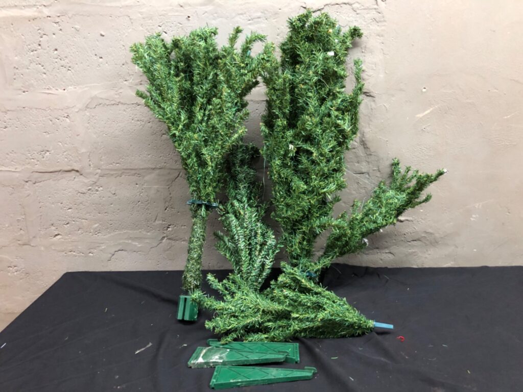 Used artificial Christmas tree – disassembled sections with green plastic base pieces (base damaged) — no stand