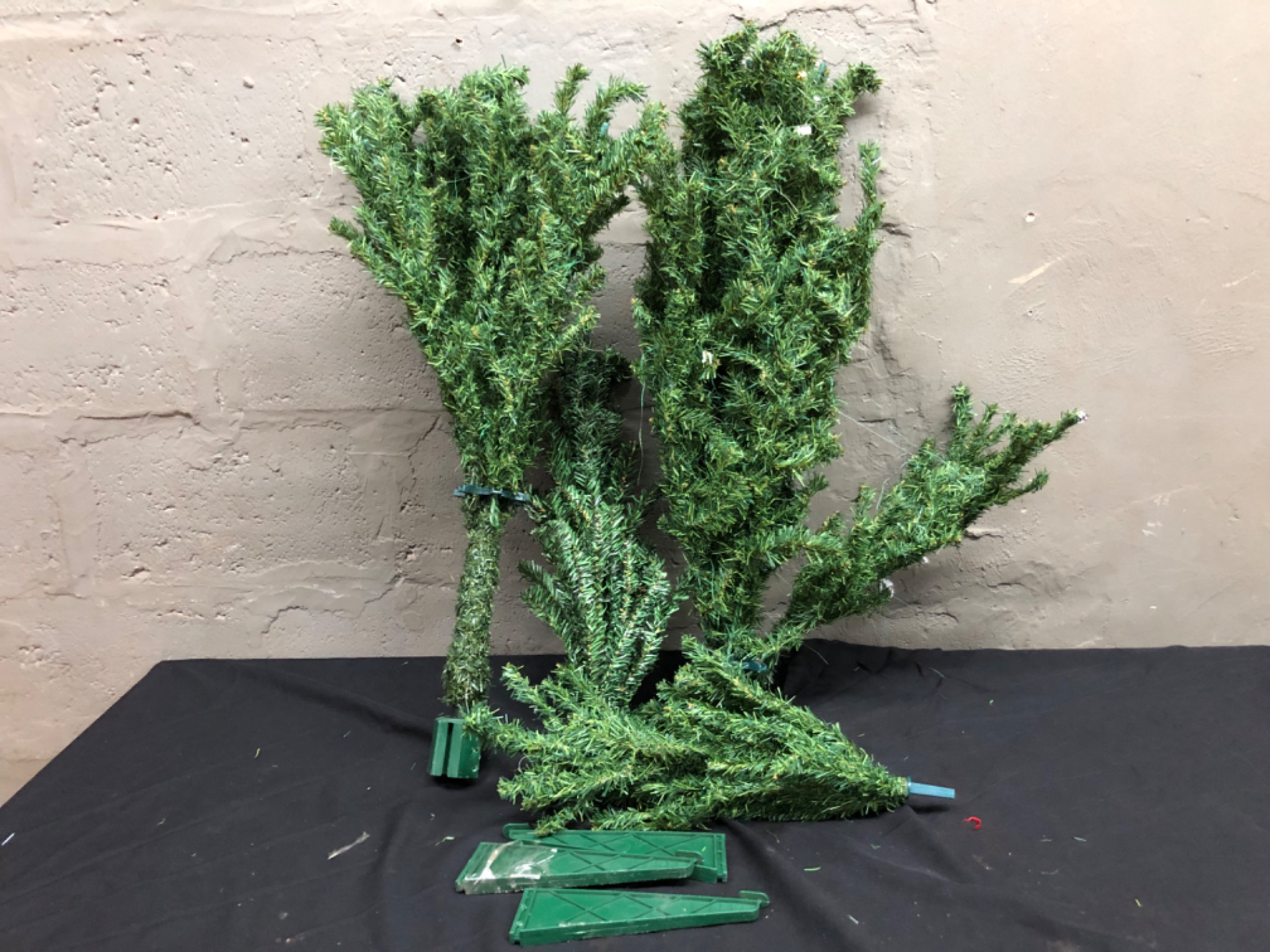 Used artificial Christmas tree – disassembled sections with green plastic base pieces (base damaged) — no stand