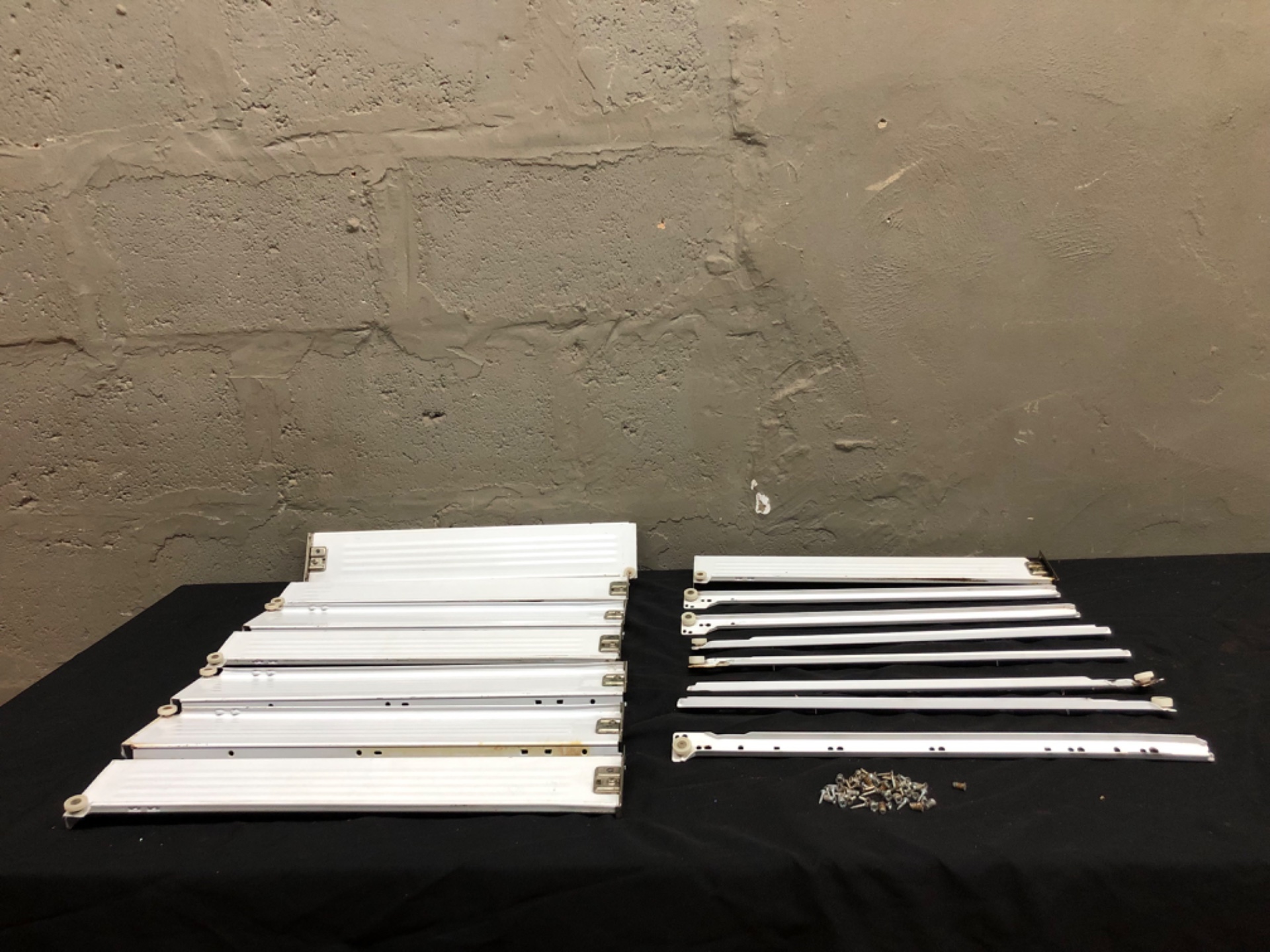 Assorted white metal drawer slides with rollers + mounting screws — 15 rails (matched pairs) and 20 screws, used/fair
