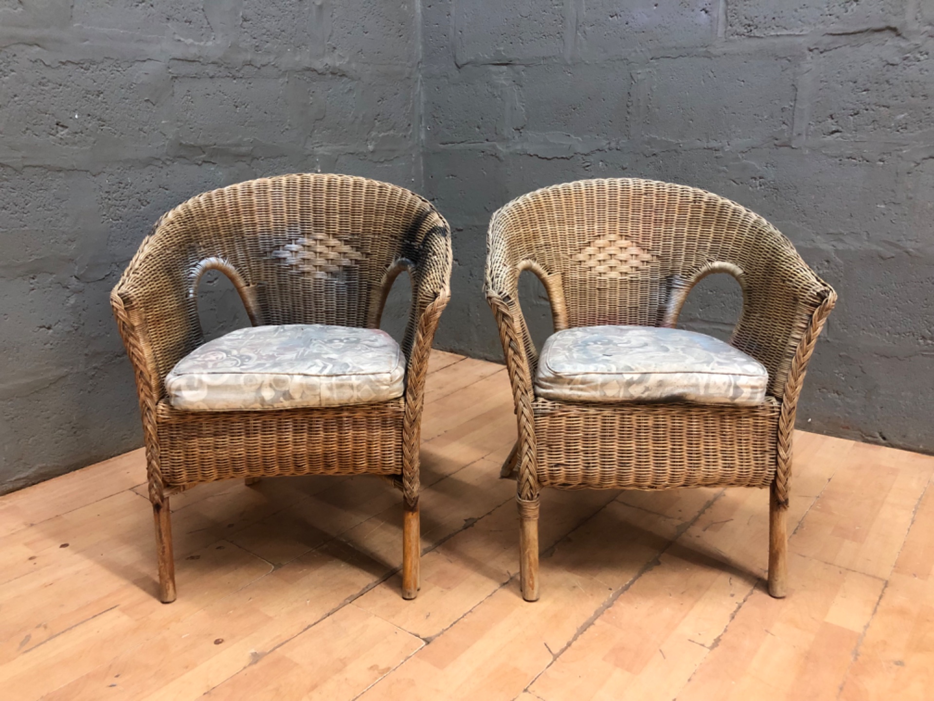 Pair of wicker / rattan armchairs with removable cushions – sound frames, worn finish & staining