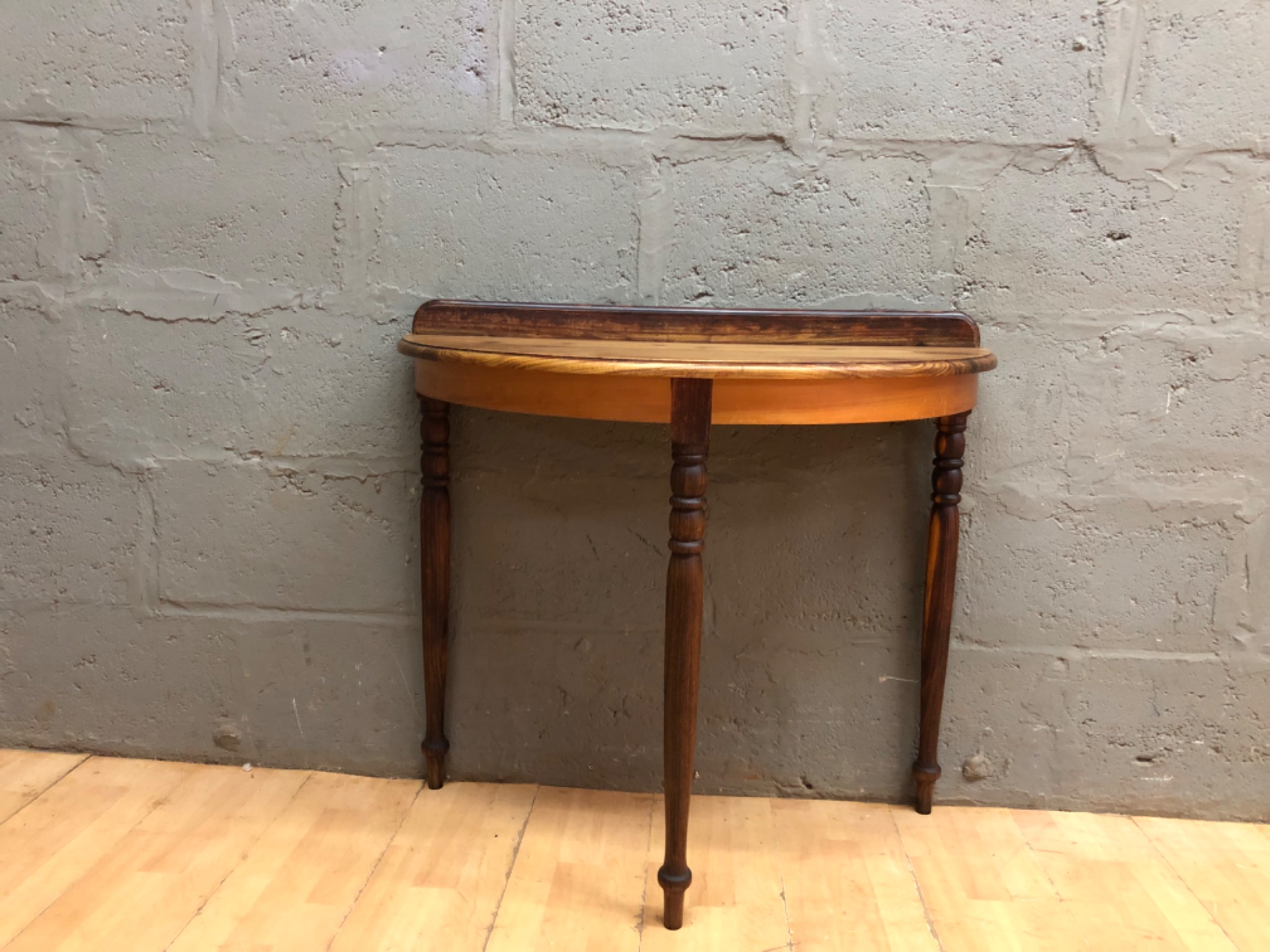 Half‑moon pine demilune console table with raised back rail and turned legs