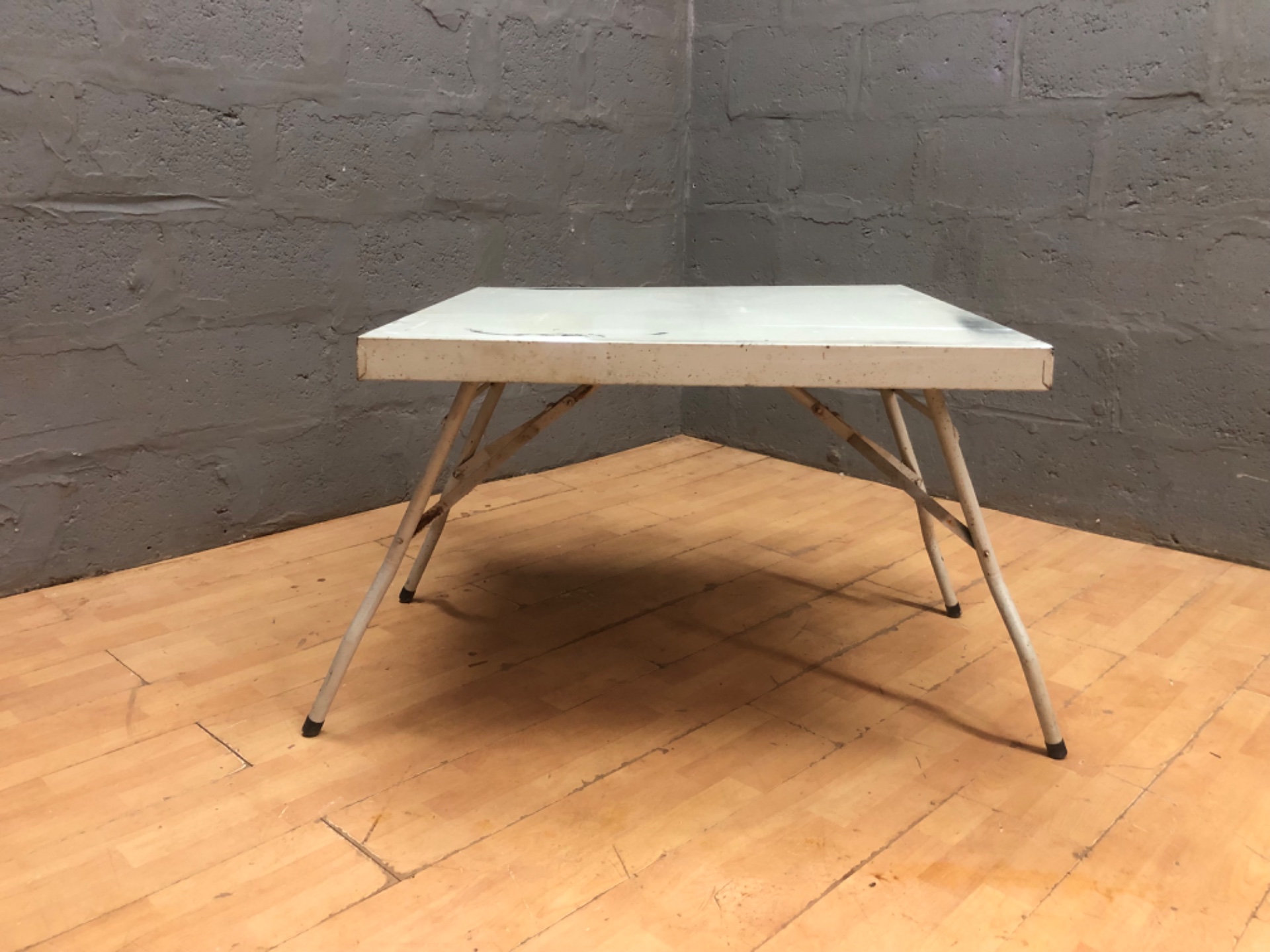 Folding work table with thick laminated top — 90 × 90 × 58 cm — paint-stained, rusted legs, bent brace