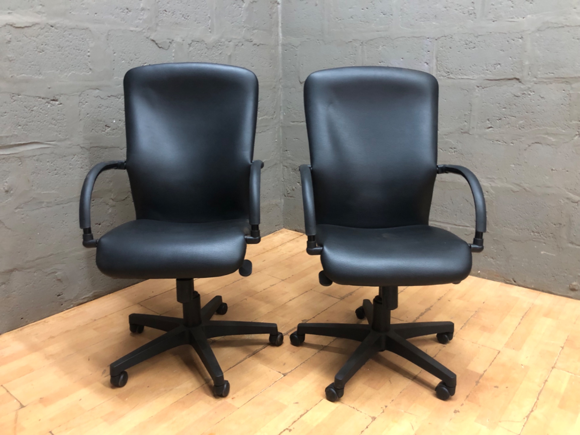 Pair of black office swivel chairs — adjustable height, five-star bases with casters