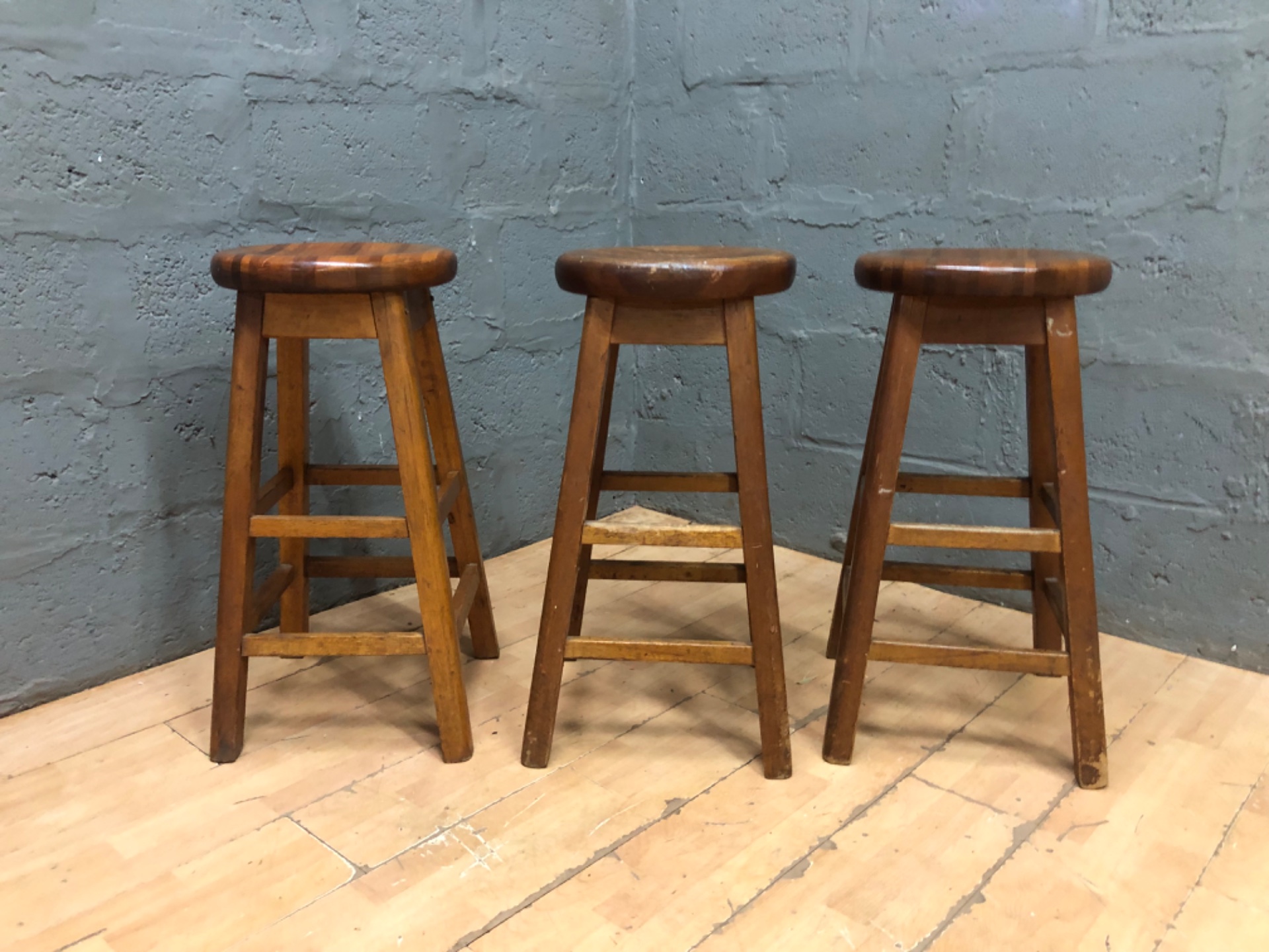 Set of 3 wooden round‑seat stools — 75 cm high, used with surface wear