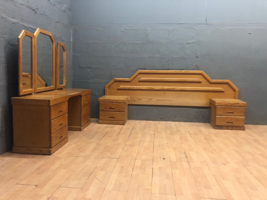 Oak‑finish bedroom suite — dressing table with tri‑fold mirror, headboard and two bedside pedestals