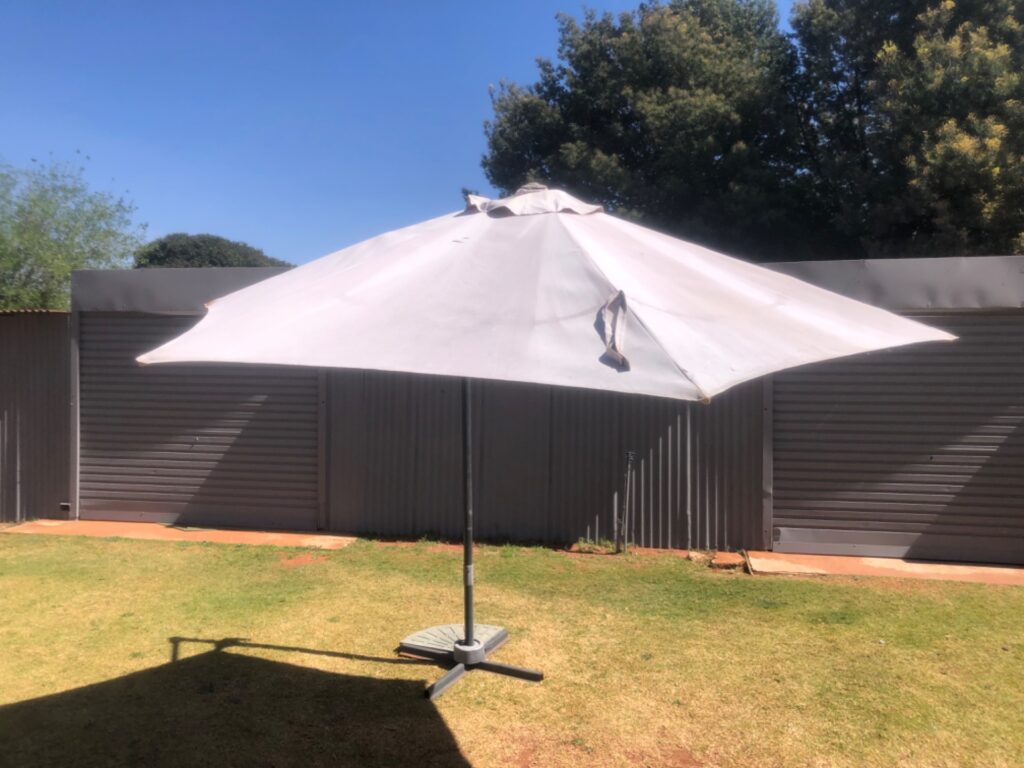 Market-style outdoor patio umbrella with cross base & concrete weight — crank tilt, used with canopy tears