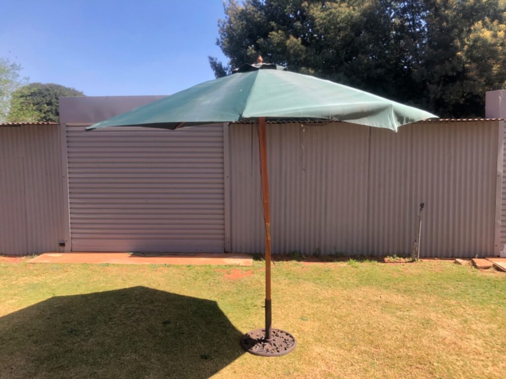 Outdoor wooden-pole patio umbrella with decorative cast-iron base — 296cm canopy, 240cm high (fair condition)