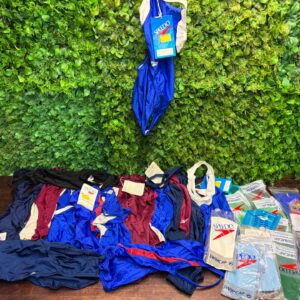 Bulk lot of Speedo one‑piece swimsuits + sealed Speedo swim caps — mixed/new tags visible