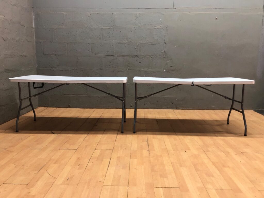 Pair of white folding plastic banquet tables — 153 x 71 x 74 cm each, one with split at centre seam