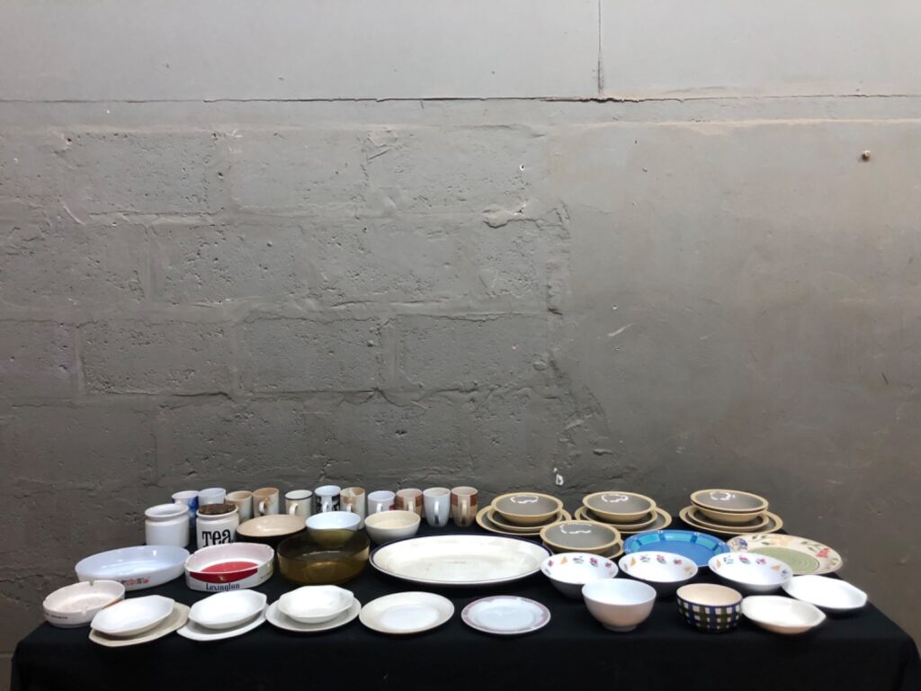 Assorted mixed dinnerware lot — approx. 50 ceramic/porcelain plates, bowls, mugs, serving pieces (mixed brands, stained/used)