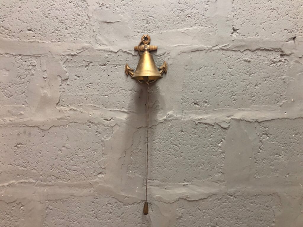 Solid brass wall-mounted nautical bell with anchor backplate — rings well