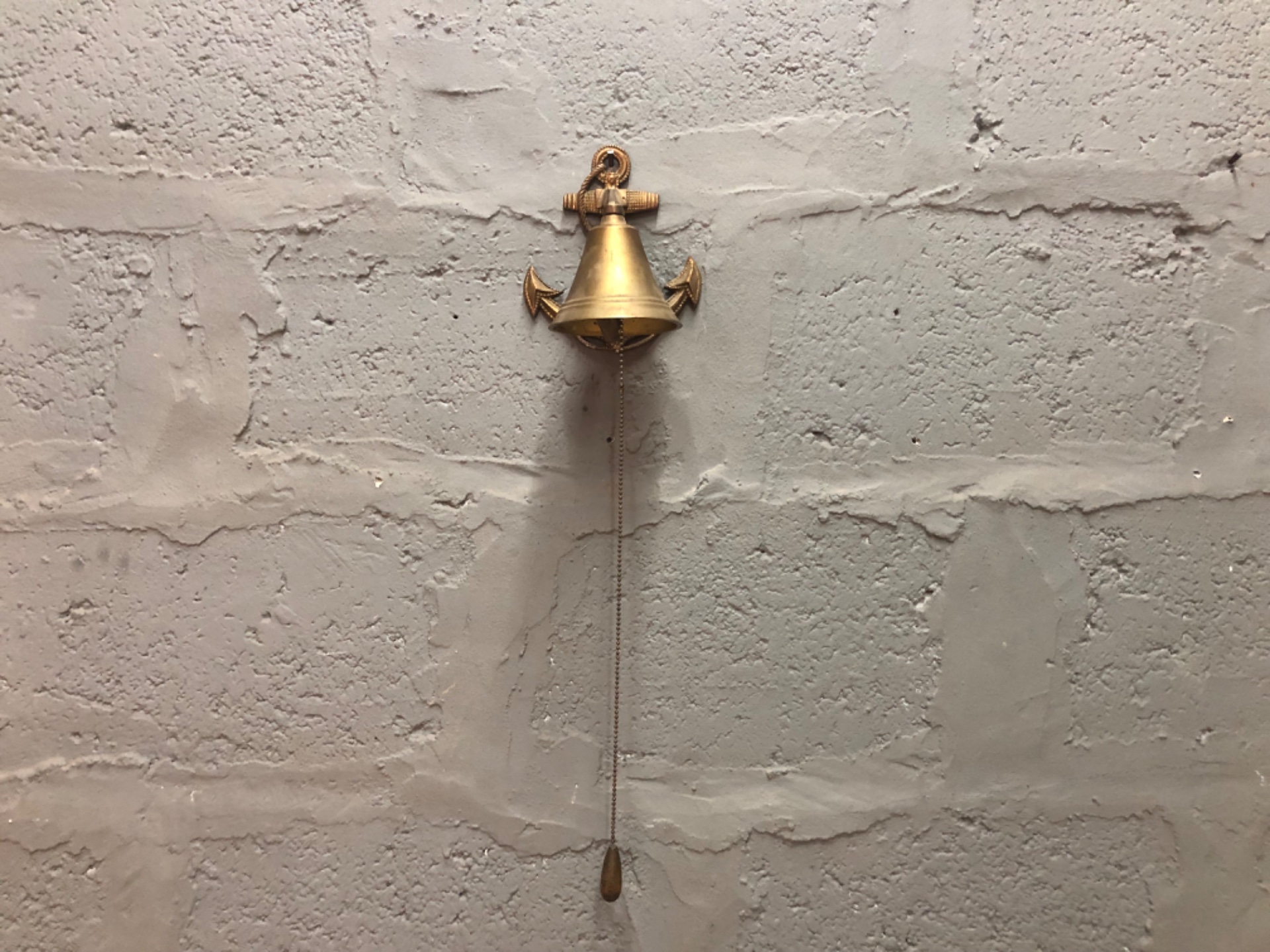 Solid brass wall-mounted nautical bell with anchor backplate — rings well