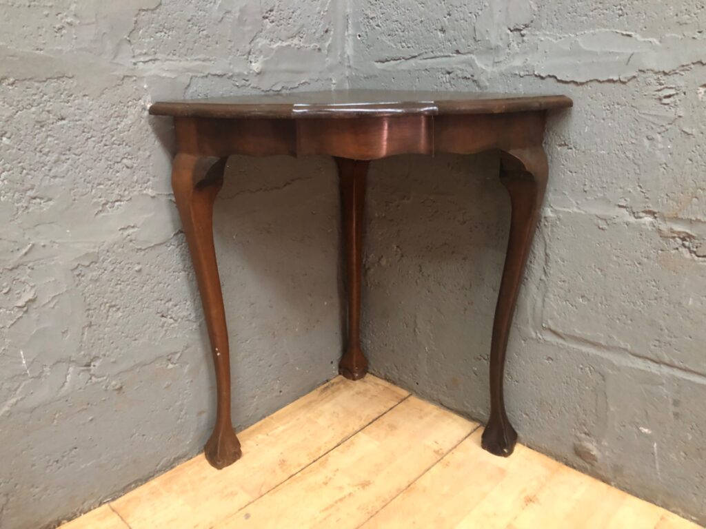 Triangular corner console table — slender cabriole legs, scalloped apron, used with surface wear