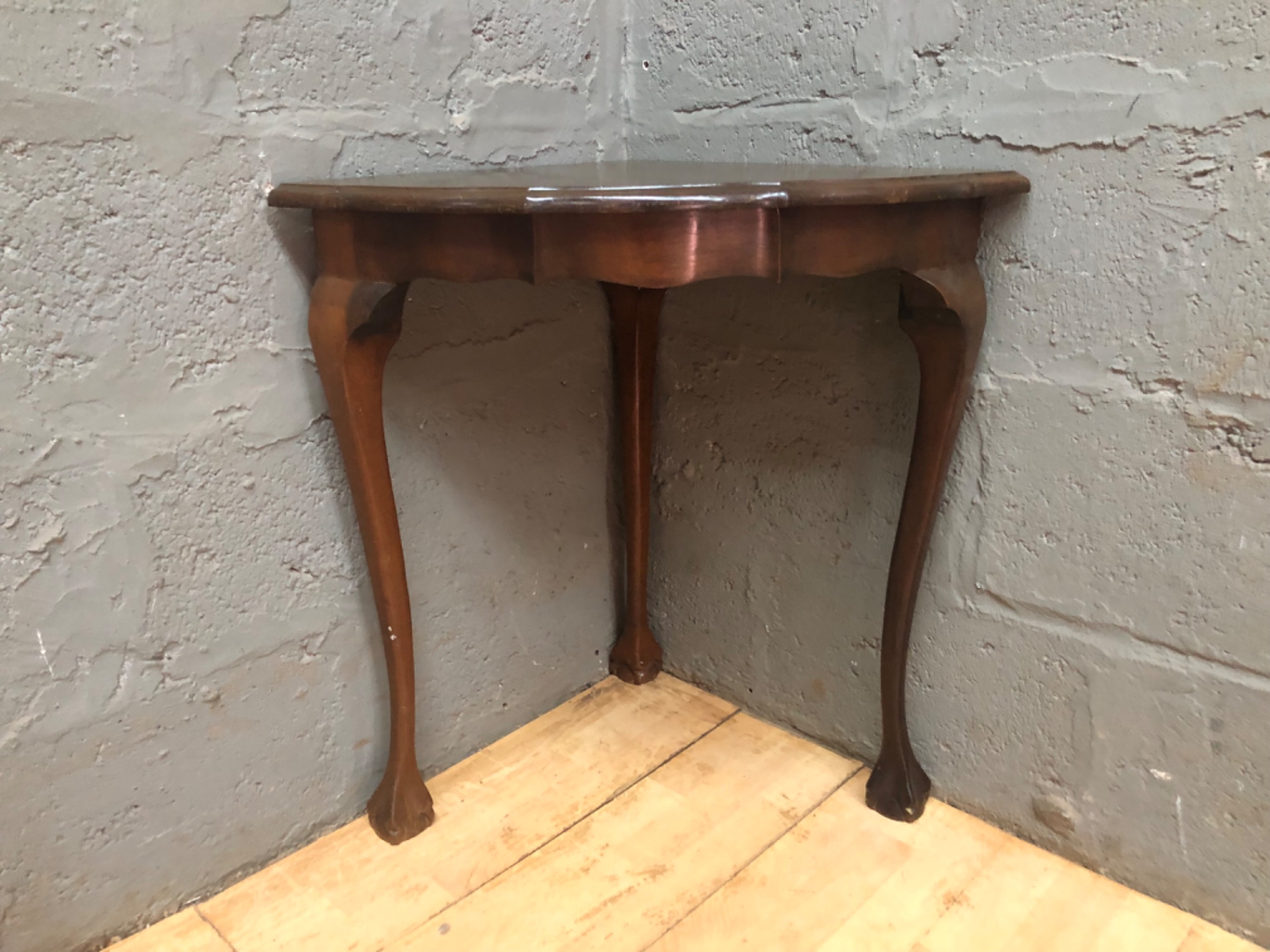 Triangular corner console table — slender cabriole legs, scalloped apron, used with surface wear