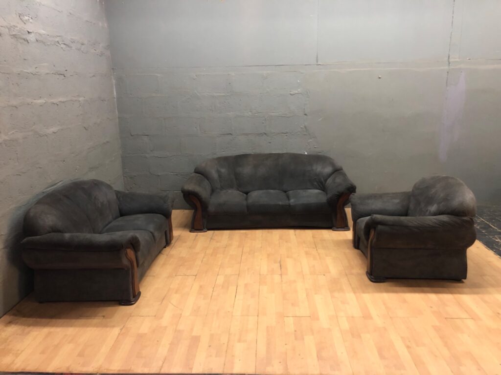 Three-piece dark grey lounge suite (sofa + 2 chairs) — heavy upholstery damage, wooden arm trim