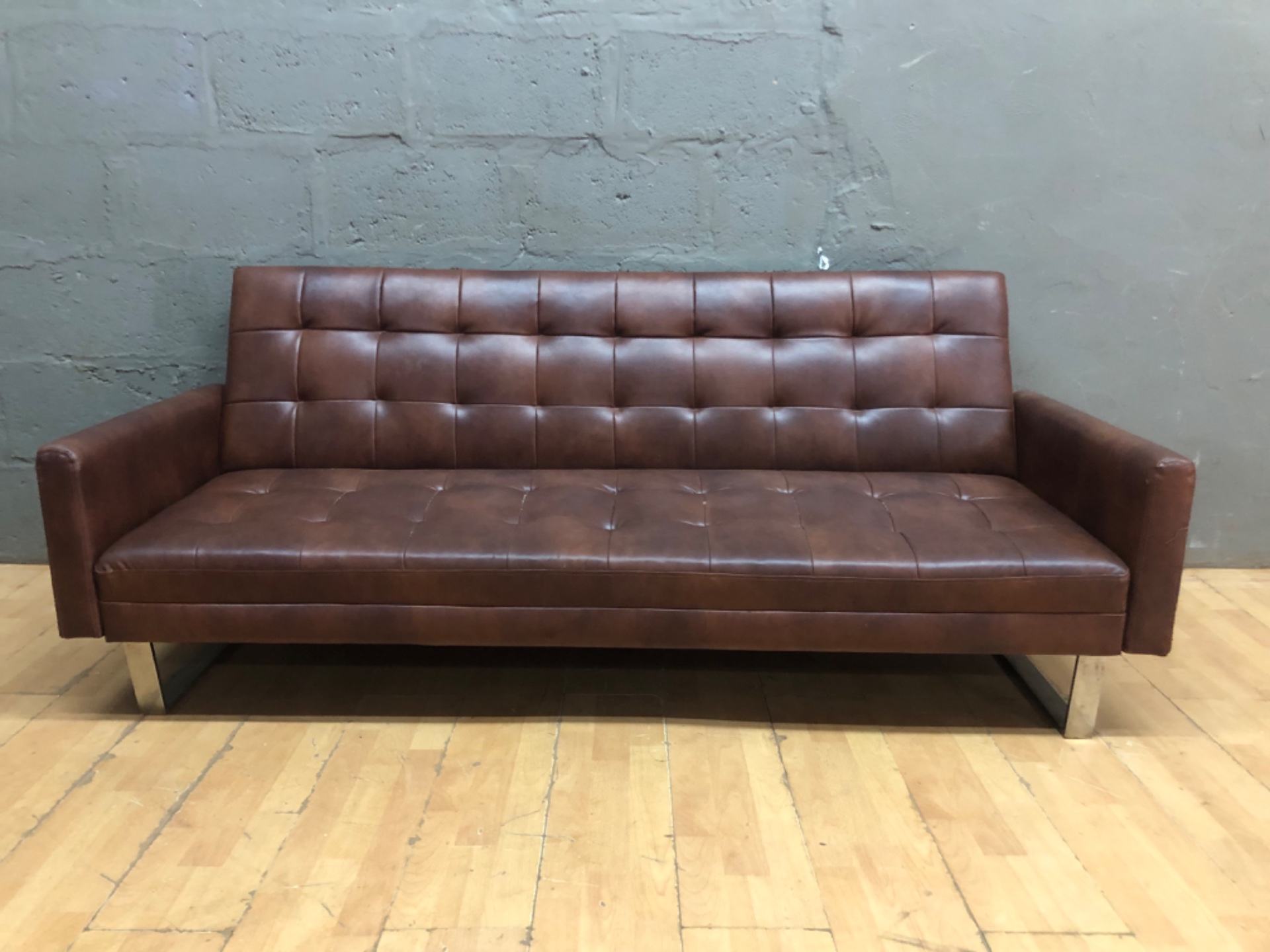 Brown tufted 3-seater genuine leather sofa bed with metal sled legs — converts to bed, visible tears and split seams