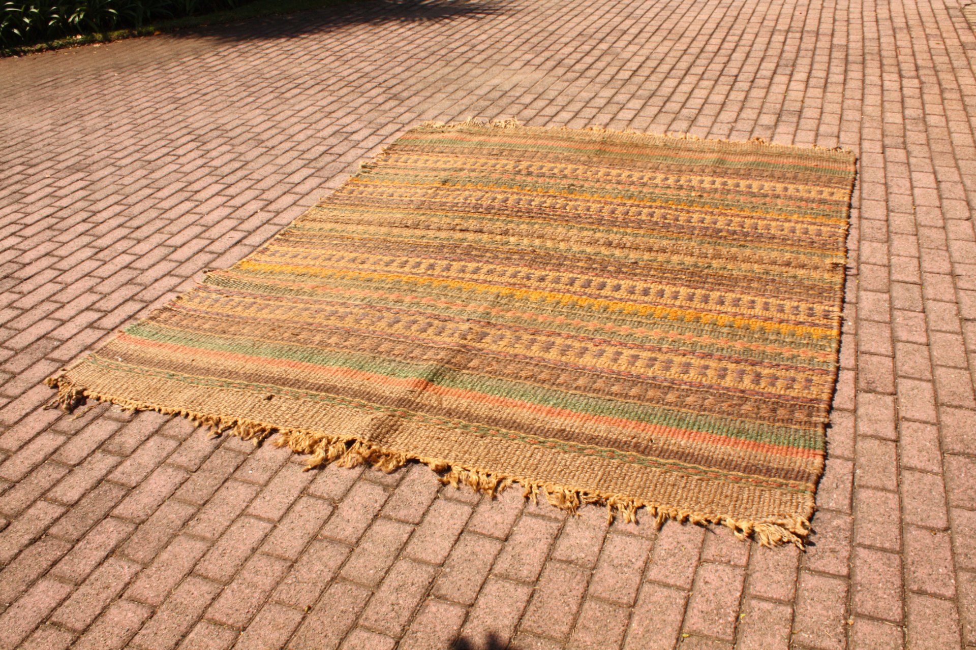 Large flatwoven striped rug — earthy tones, approx 200 × 200 cm, visible wear & frayed edges