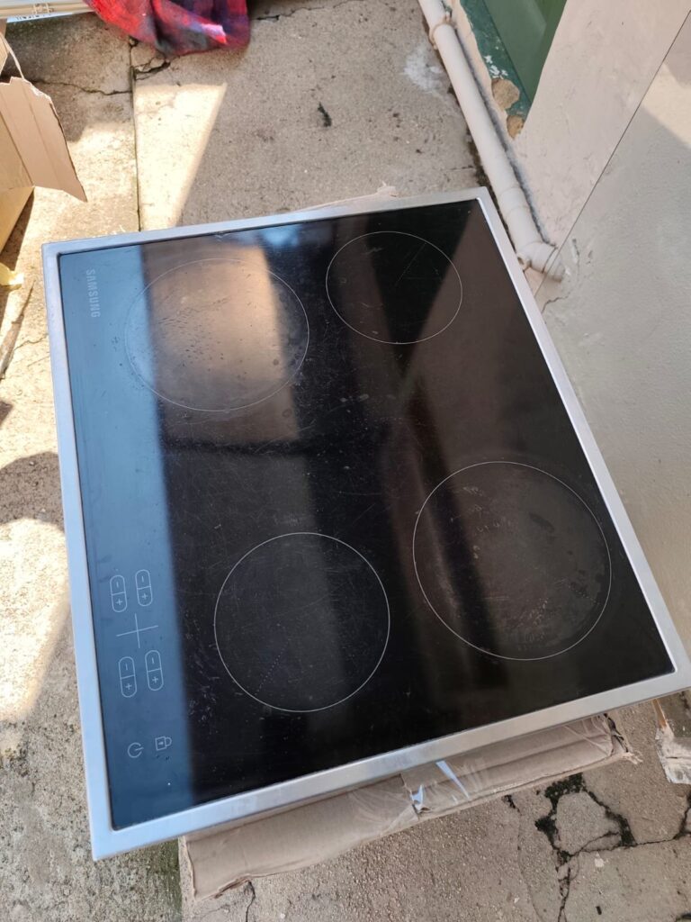 Samsung 4-zone ceramic glass electric hob — working, heavy surface wear and pitted left zone