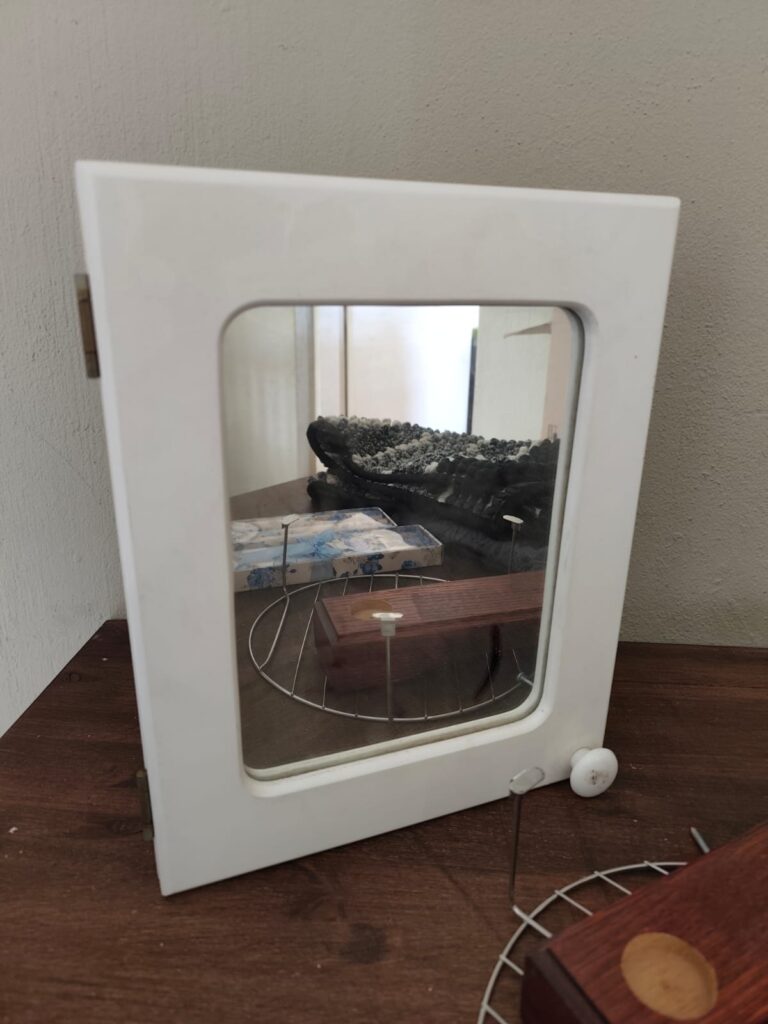 Mixed home lot: white mirrored wall cabinet, wooden display stand, round metal rack, 2 boxed taper candle sets, folded rugs/mats