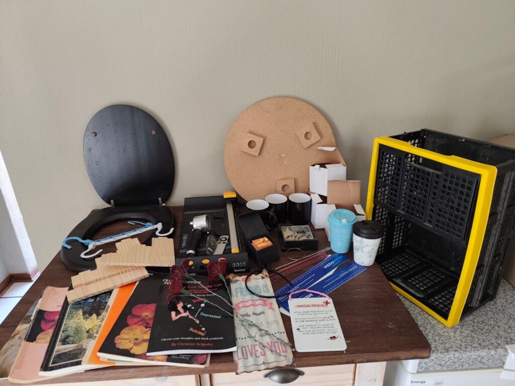 Mixed household lot — plastic crate, Fellowes paper trimmer, mugs, coasters, books & small decorative/tools