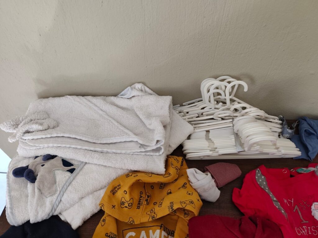 Mixed baby / toddler clothing bundle with hooded towels + white plastic hangers — used, assorted (tag 6-12M visible)