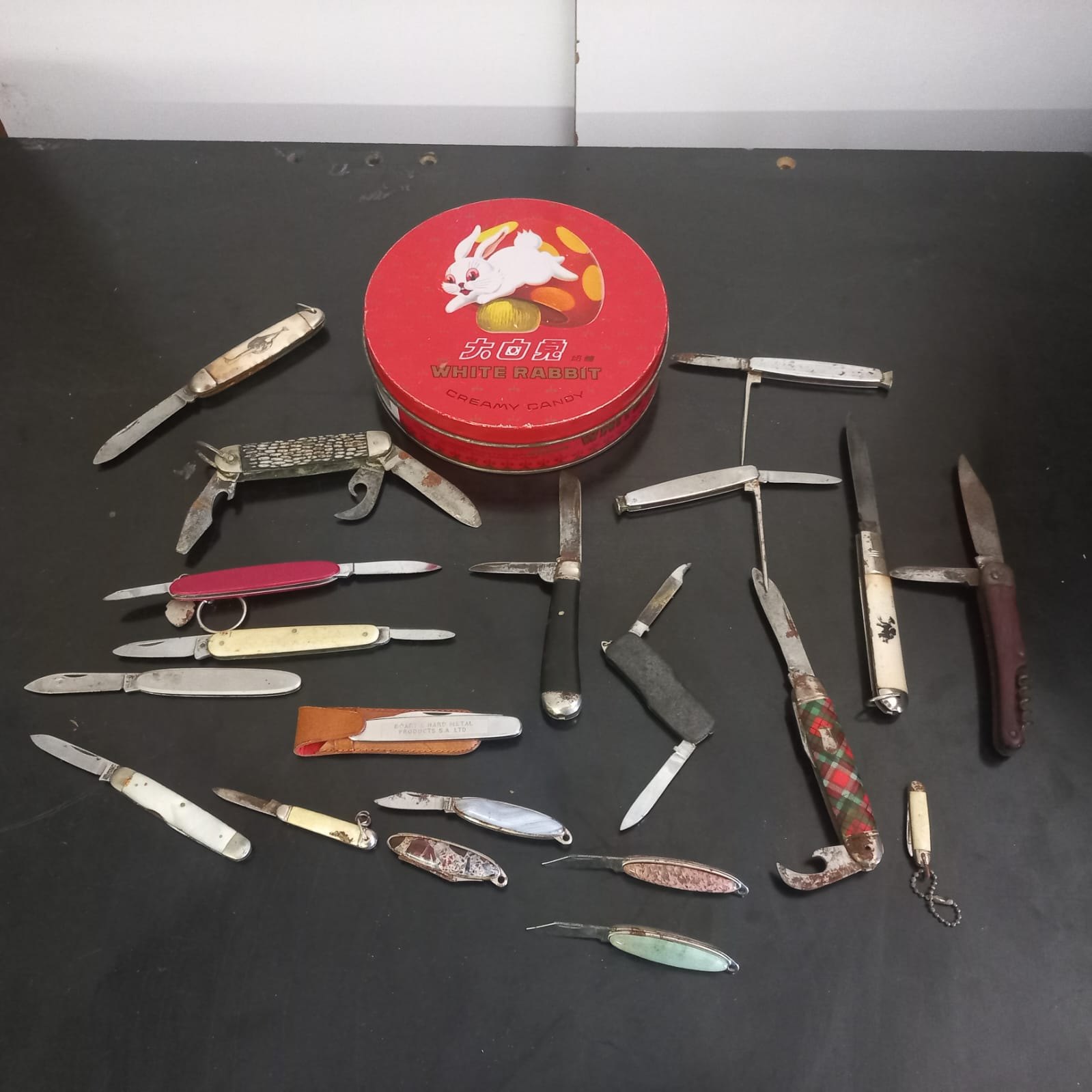 Lot of 20 vintage folding pocket knives & multi-tools (mixed makers) with red White Rabbit tin — heavy wear, rusted, restoration project