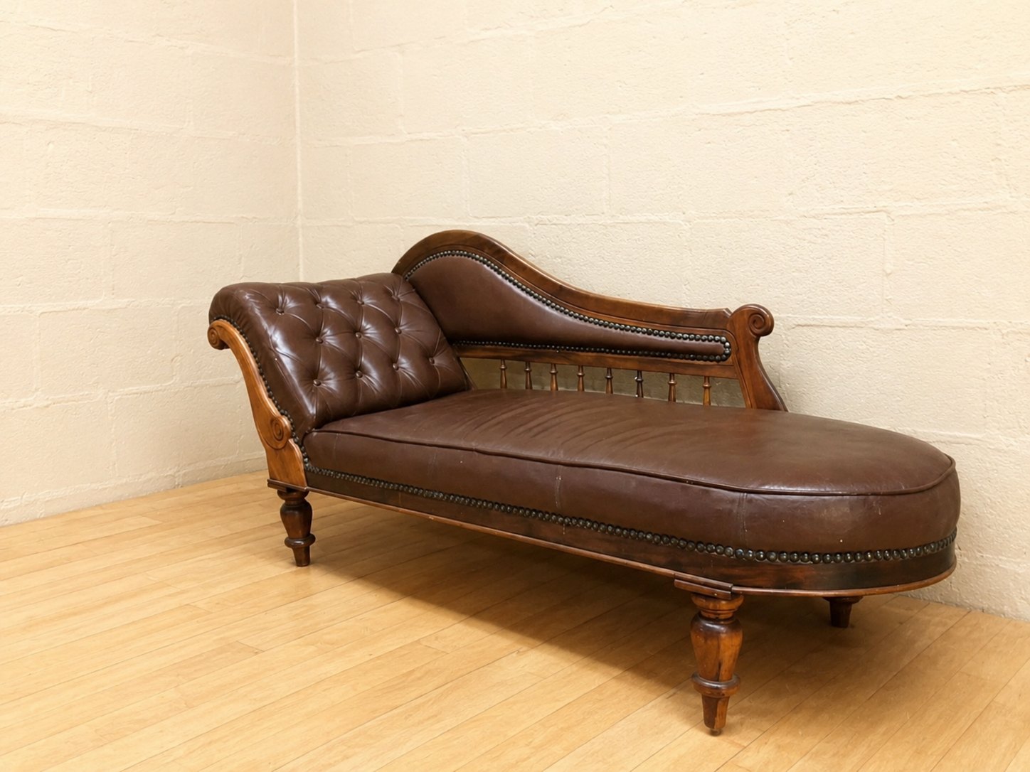 Brown tufted leather chaise longue on carved wooden frame — nameplate ‘Jonker Stinkhout, Knysna’