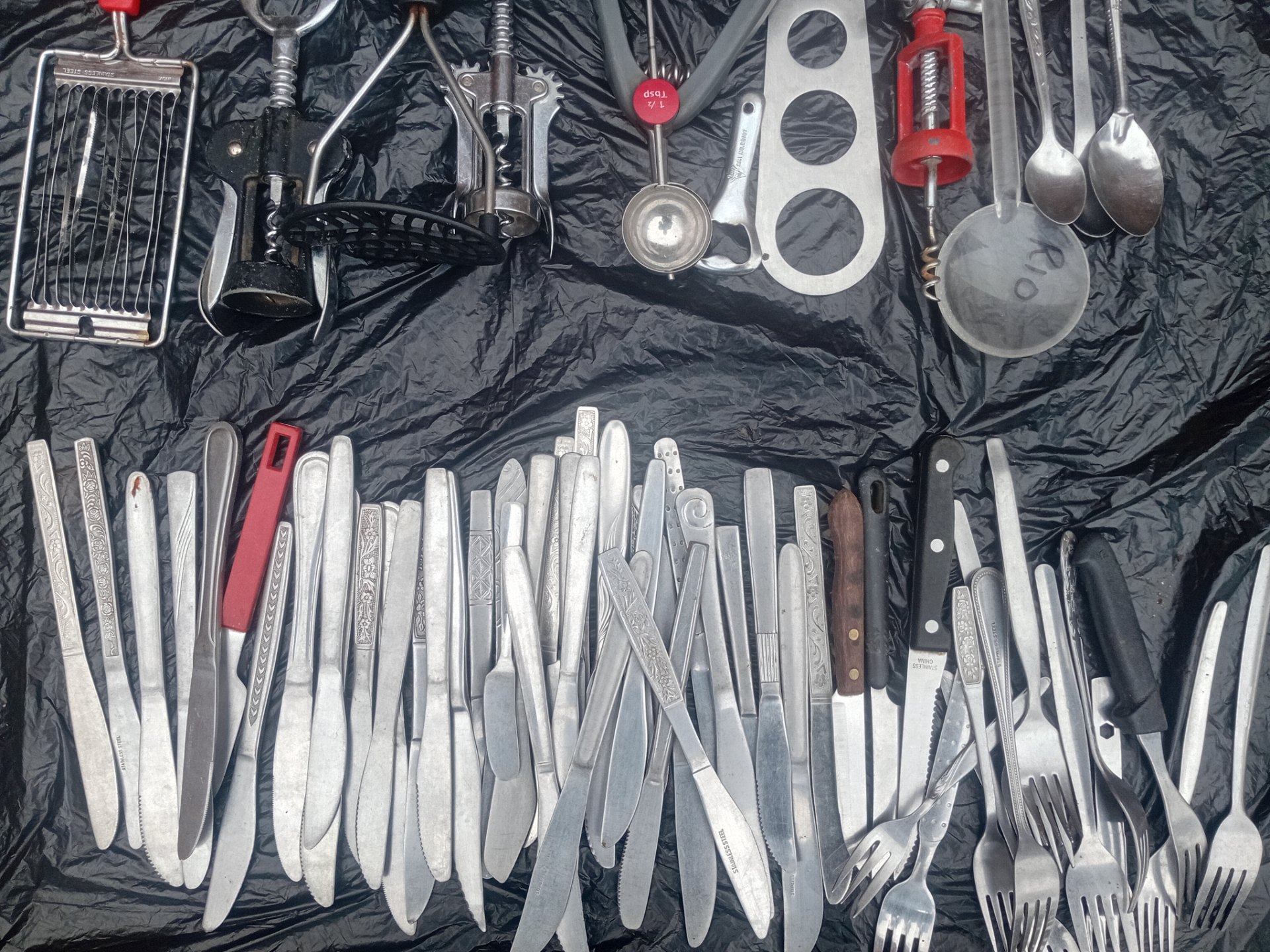 Bulk mixed cutlery & small kitchen utensils — mostly stainless-steel knives, forks & spoons with corkscrews, scoops and tools (used, surface tarnish & light rust)