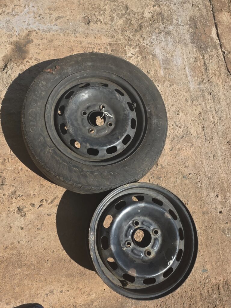 Pair of Ford‑stamped steel wheels — 2 rims (1 with tyre, 145/65R14 visible) — used, cosmetic rust