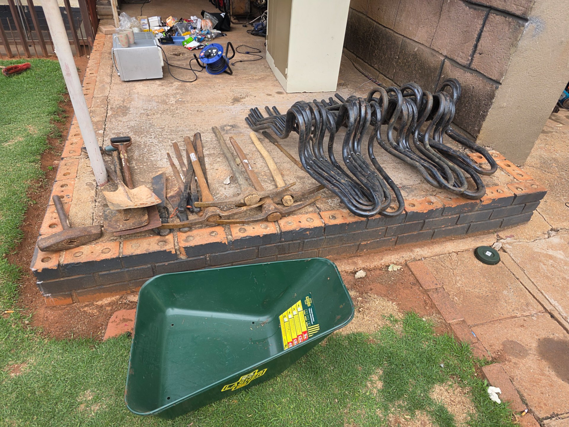 Mixed job lot: 29 garden/hand tools + 12 black curved metal frames, 2 wheelbarrow frames & Lasher wheelbarrow tub (tub missing wheel/handles)