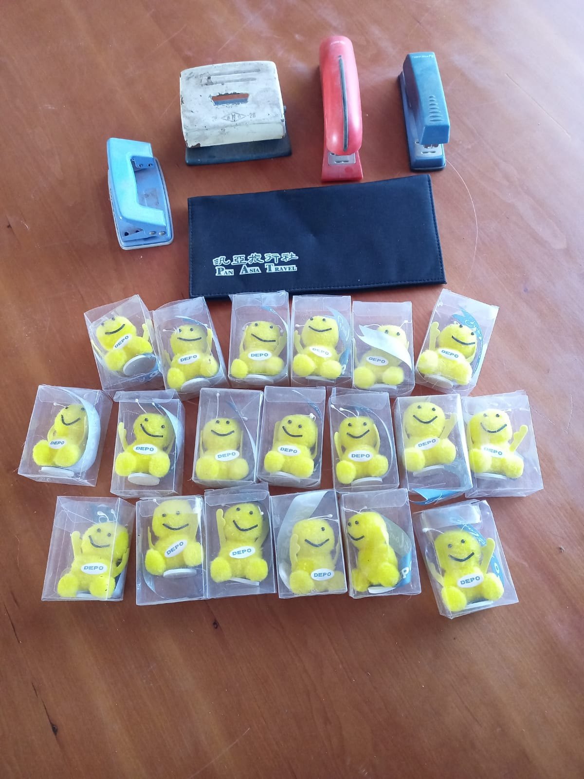 Lot 11 — Assorted office tools: 19 boxed yellow DEPO plush keyrings, 4 manual staplers/hole-punchers & Pan Asia Travel pouch