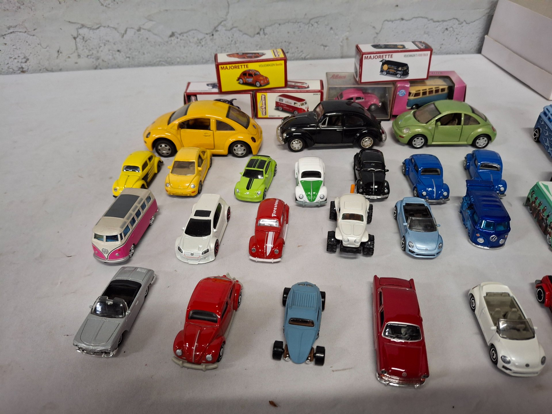 Mixed lot ~30 die‑cast toy cars — assorted loose models plus several boxed Majorette VW Beetle / T1 buses (used, visible wear)