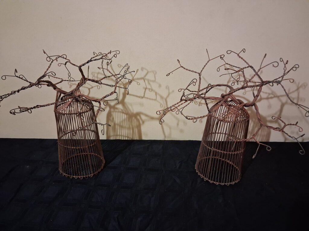 Pair of copper‑coloured twisted‑wire tree sculptures on cage bases
