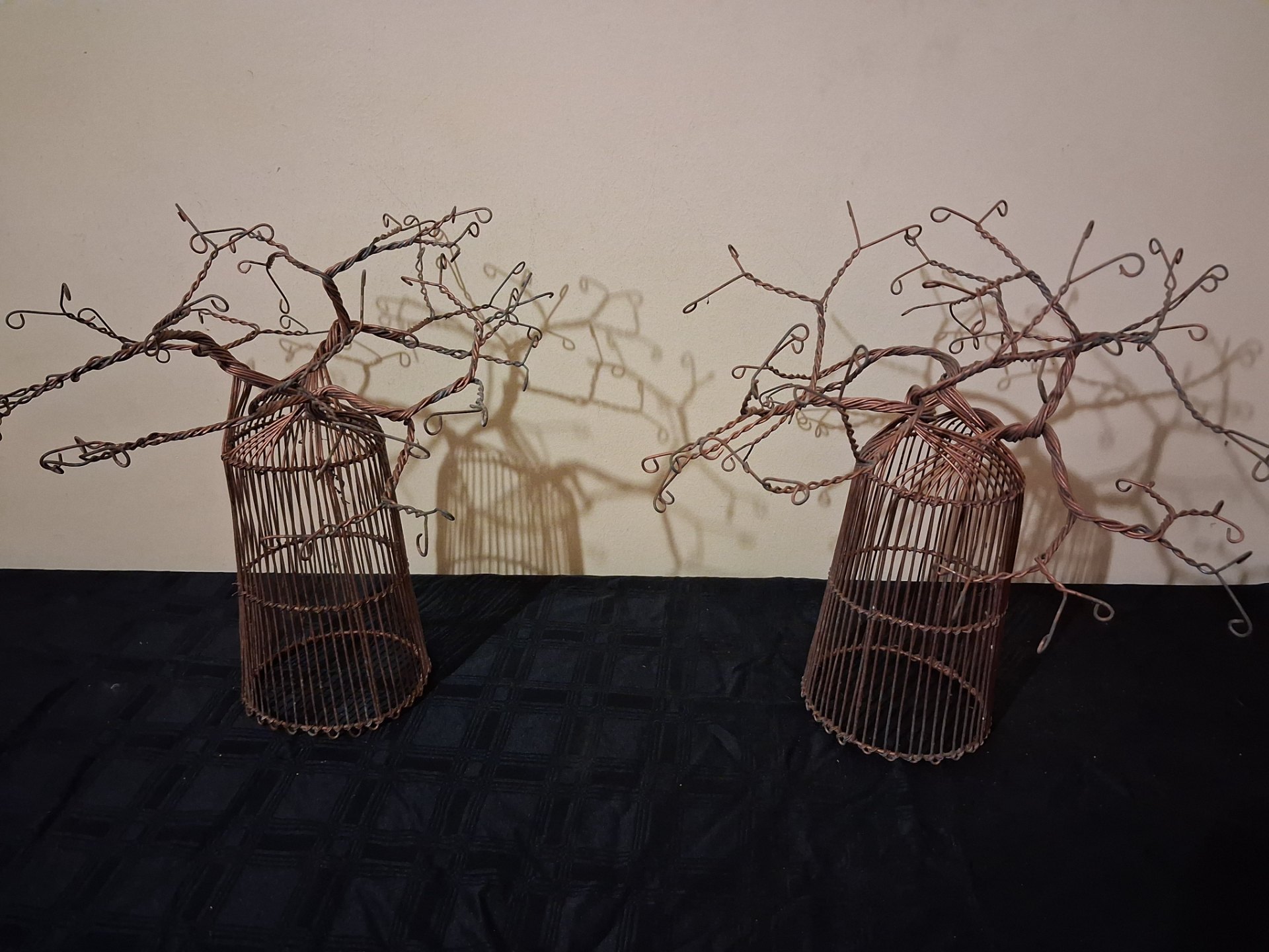Pair of copper‑coloured twisted‑wire tree sculptures on cage bases