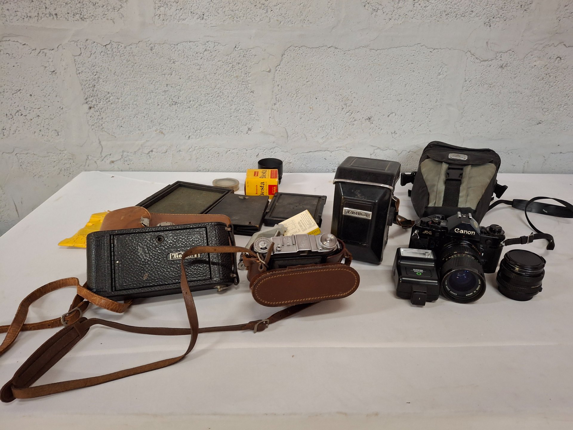 Mixed lot vintage film cameras & accessories — Canon A‑1, lenses, Sunpak flash, Yashica case