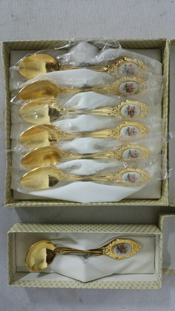Boxed set of decorative gold‑tone teaspoons with porcelain floral medallions (6 small + 1 larger)