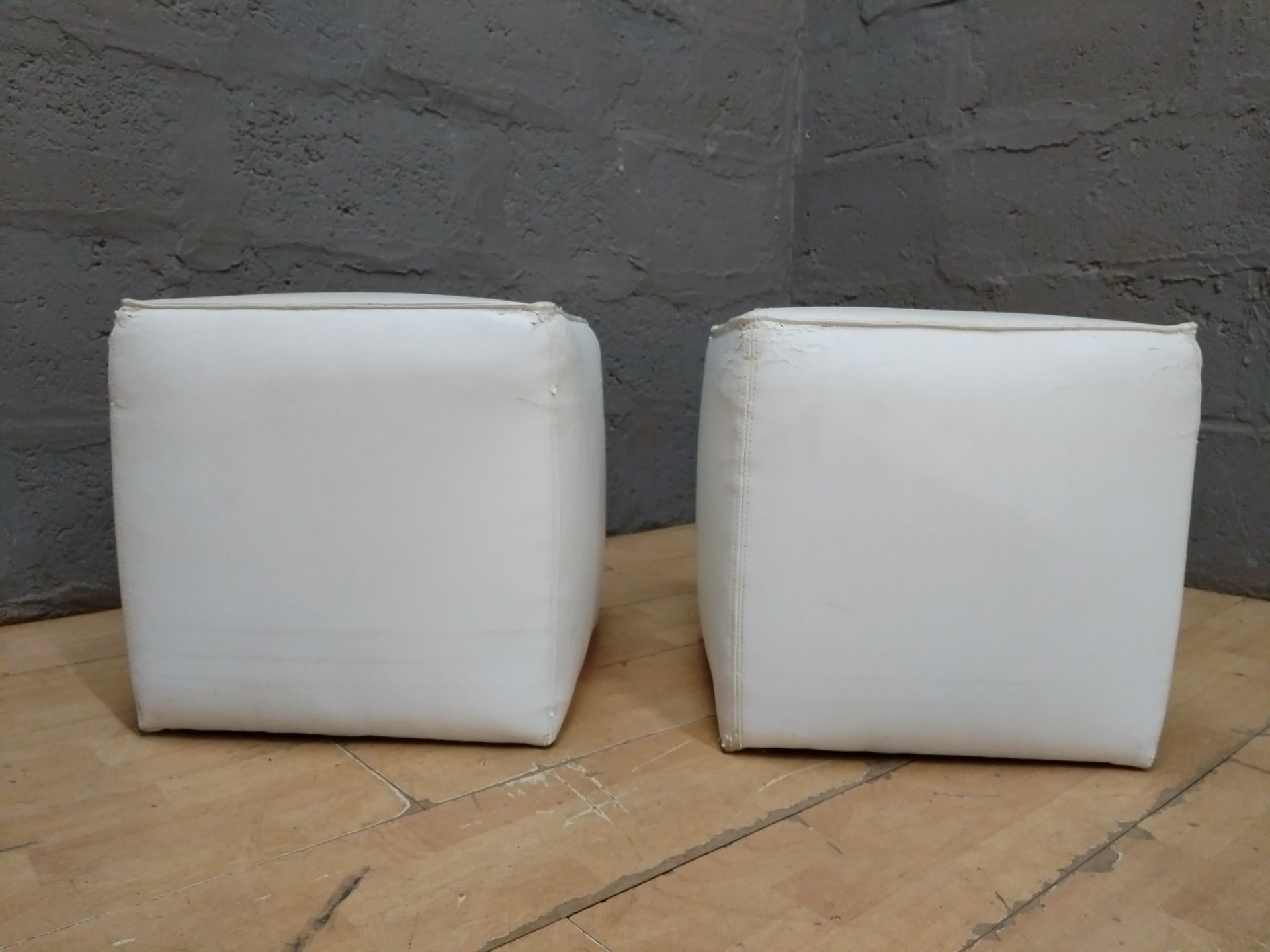 Pair of white cube ottomans / footstools – faux leather, heavy surface wear
